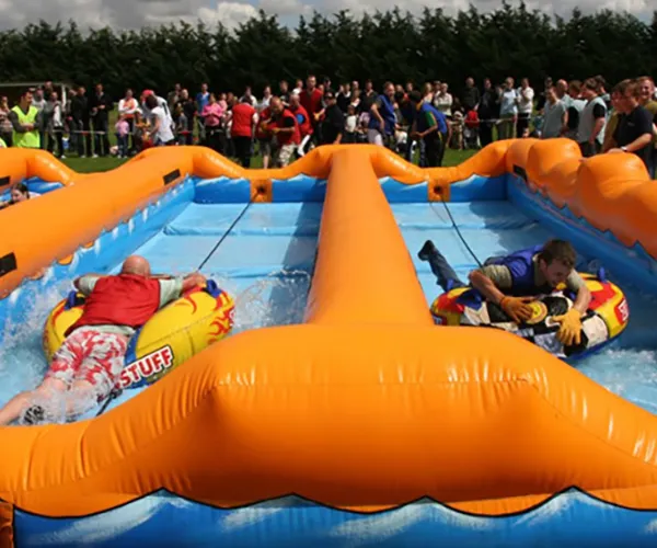 2 men, each on a pool floater inside an inflatable pool during their team building event.
